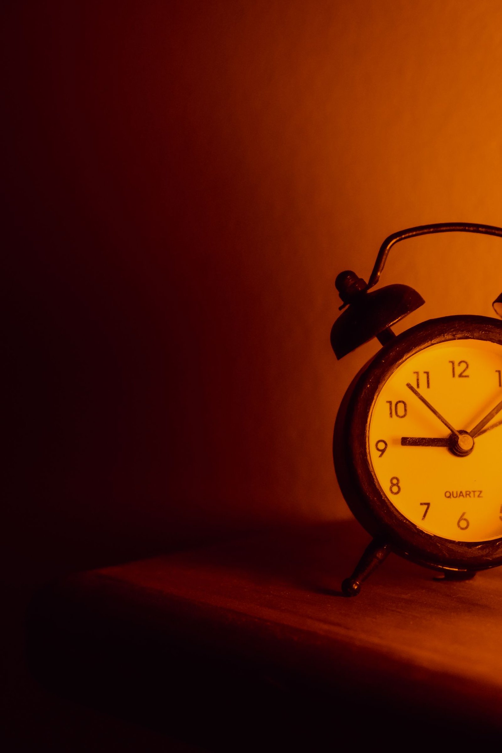 Classic analog alarm clock on a wooden surface in warm lighting, symbolizing time and tradition.