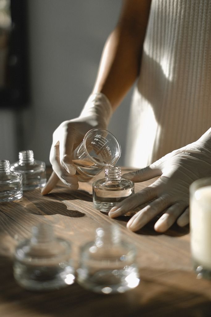 Unrecognizable crop African American female pouring essential oil in glass bottle while preparing liquid incense